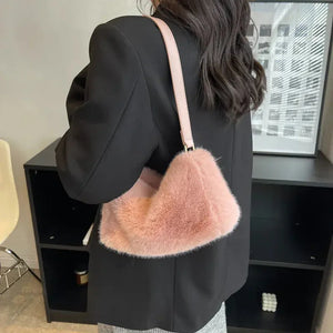 Woman wearing a black blazer with a pink faux fur shoulder bag