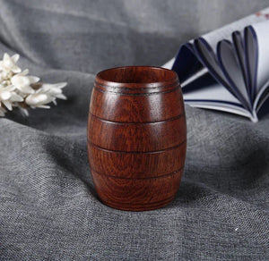 Wooden barrel-shaped cup on gray fabric, rustic drinkware decor style.