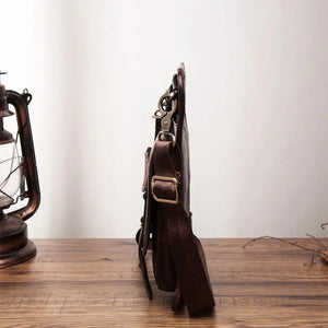 Side view of slim brown leather crossbody bag with adjustable strap on wooden table