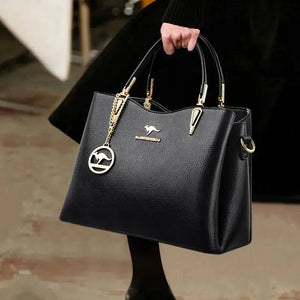 Elegant black leather handbag with gold hardware and kangaroo charm, held by a woman