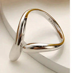 Minimalist sterling silver twisted open ring on a neutral background