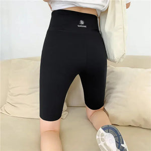 Woman wearing black high-waisted biker shorts with 'Sunshine' logo, casual setting