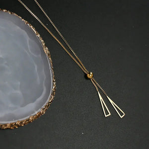 Gold geometric pendant necklace on black background with agate stone accent