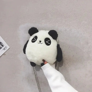 Plush panda-shaped crossbody bag with chain strap held against a light wall
