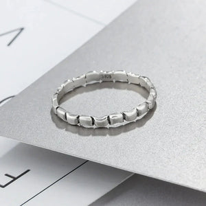 Sterling silver textured band ring with geometric links on a minimalist background
