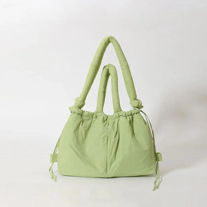 Light green fabric tote bag with padded handles and knotted accents on a white background