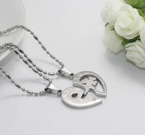 Silver heart-shaped couple necklaces with 'love you' engraving on white background