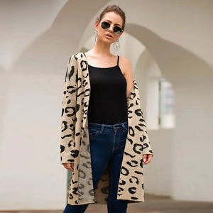 Woman wearing beige leopard print cardigan, black top, blue jeans, and sunglasses outdoors