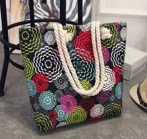 Colorful floral print tote bag with thick twisted rope handles on a gray floor