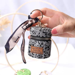 Hand holding a sparkly black sequin mini bag keychain with zipper and ribbon accent