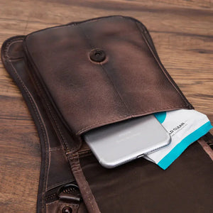Brown leather pouch with phone and wipes on wooden surface