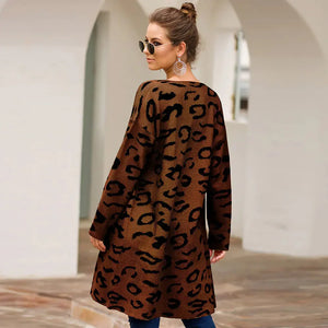 Woman wearing long leopard print cardigan, standing outdoors in casual fashion.
