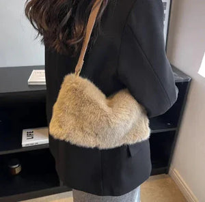 Woman wearing a black blazer and carrying a beige faux fur shoulder bag indoors
