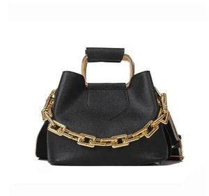 Black leather handbag with gold chain strap and metal handle on white background