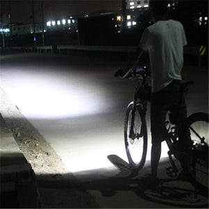 Cyclist with bicycle LED headlight illuminating dark road at night
