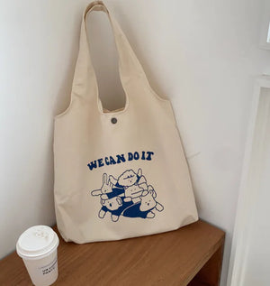 Canvas tote bag with cute animal print and 'We Can Do It' text on a wooden table