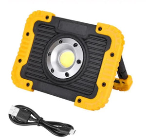 Portable LED work light with yellow and black casing, stand, and USB charging cable