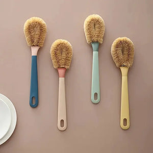 Set of four dish brushes with natural bristles and pastel handles on a beige background