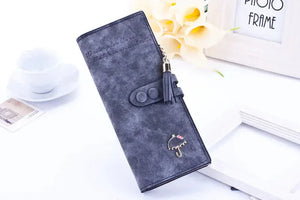 Gray women's long wallet with tassel, umbrella charm, and snap closure on white background