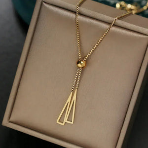 Gold geometric pendant necklace on beige jewelry box
