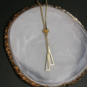 Gold geometric pendant necklace with adjustable chain on decorative dish