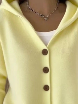 Light yellow button-up cardigan with hood, layered over white top, worn with chain necklace