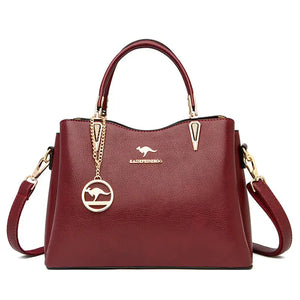 Burgundy leather handbag with gold chain, top handles, and detachable shoulder strap