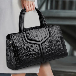 Woman holding black crocodile-embossed handbag, luxury fashion accessory