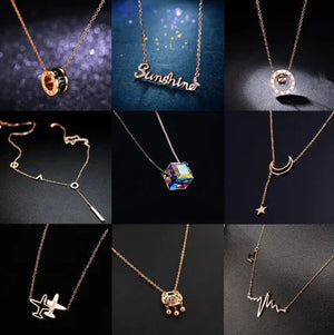 Assorted gold necklaces with unique pendants, including cube, moon, airplane, and word designs.