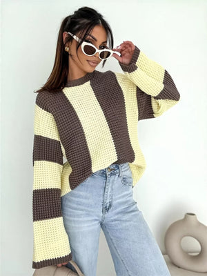 Woman in brown and yellow striped knit sweater, light blue jeans, and white sunglasses