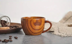 Wooden coffee cup on stone surface with coffee beans and rustic fabric