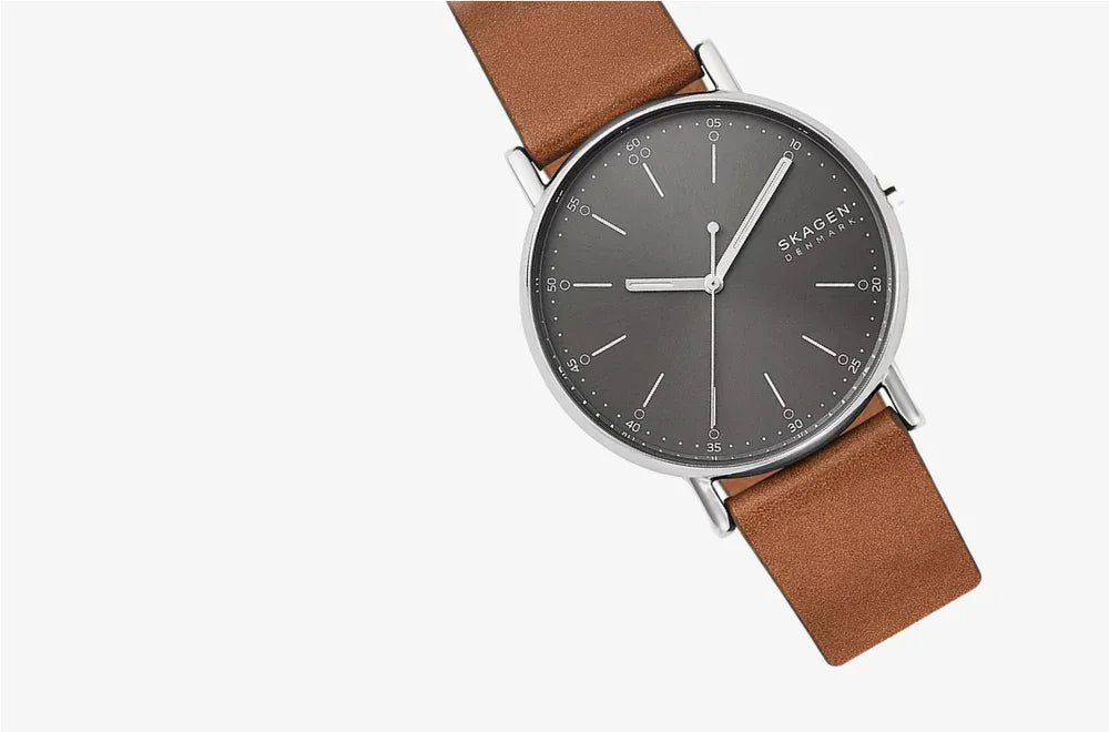 Minimalist men's watch with brown leather strap and grey dial on white background