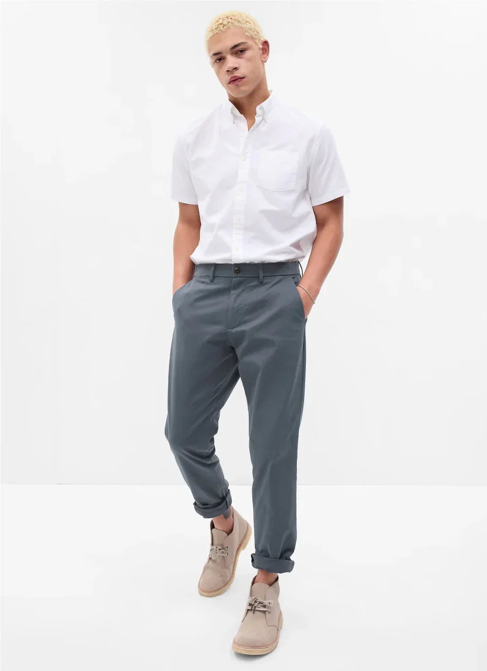 Man in short-sleeve white button-up shirt, slate blue trousers, and beige shoes, casual style