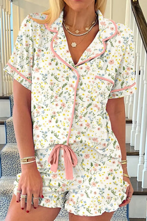 Woman wearing short sleeve floral print pajama set with pink trim and ruffle shorts