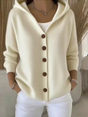 Woman wearing a cream button-up knit hoodie cardigan with pockets and white pants