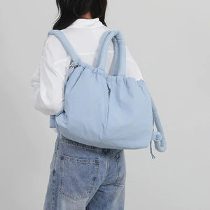 Woman wearing a light blue puffer backpack with drawstring closure, casual outfit