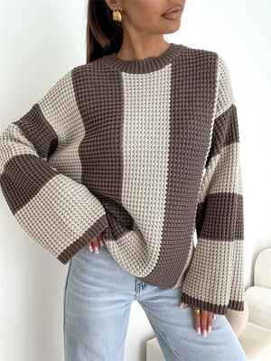 Woman wearing a brown and beige colorblock knit sweater with wide sleeves and light blue jeans