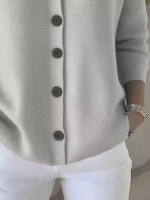 Light gray button-up cardigan with three-quarter sleeves and white pants