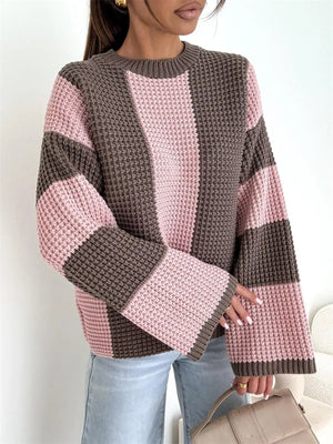 Woman wearing a pink and brown knit sweater with wide sleeves and light blue jeans
