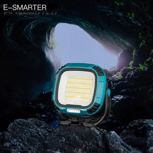 Portable LED work light with teal frame displayed on rocks inside a dark cave