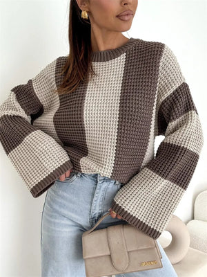 Woman wearing a brown and beige colorblock knit sweater with light wash jeans and a beige purse