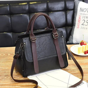Black and brown leather handbag with shoulder strap on a wooden table, cafe setting