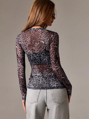 Woman wearing sheer leopard print long sleeve top with light grey jeans, back view