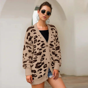 Woman wearing beige leopard print cardigan, black top, denim shorts, sunglasses, and earrings.