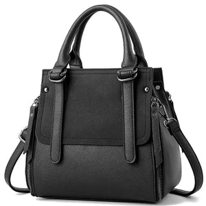 Black leather handbag with top handles and detachable shoulder strap, front zip details