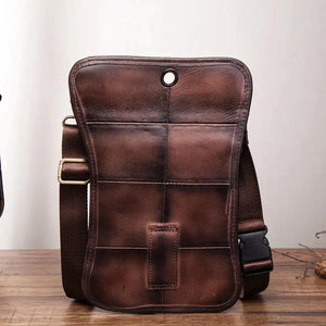 Brown leather crossbody bag with adjustable strap and stitched grid pattern on wood table
