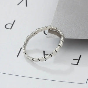 Textured sterling silver ring with unique segmented design on a minimal background