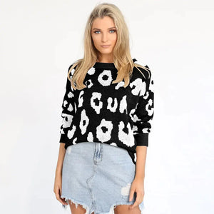 Woman in black and white leopard print sweater and distressed denim mini skirt
