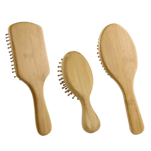 Set of three natural bamboo wooden hair brushes with different shapes on white background