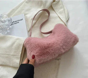 Pink faux fur shoulder bag on cream blazer, hand with red nails holding strap